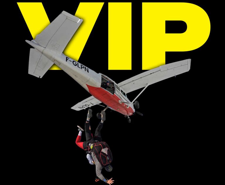 Duo en saut tandem quittant un petit avion en vol, avec l’inscription « VIP » en grand arrière‑plan.